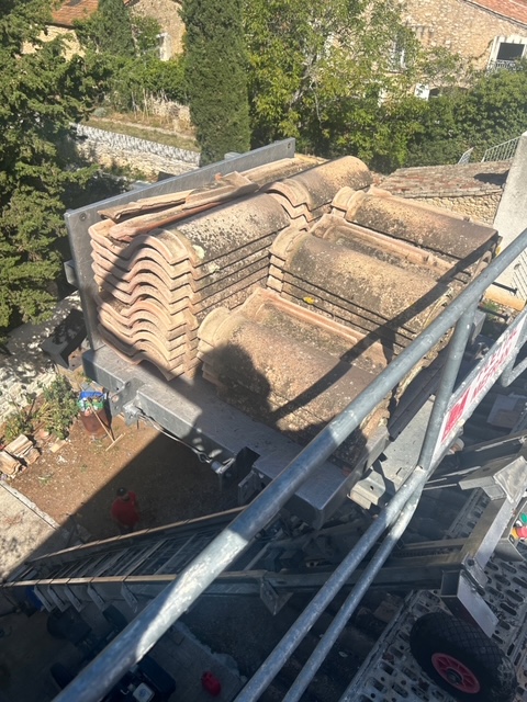 Tuiles canal anciennes déposées et empilées sur le plancher d'un échafaudage monté le long de la maison, vues depuis le toit